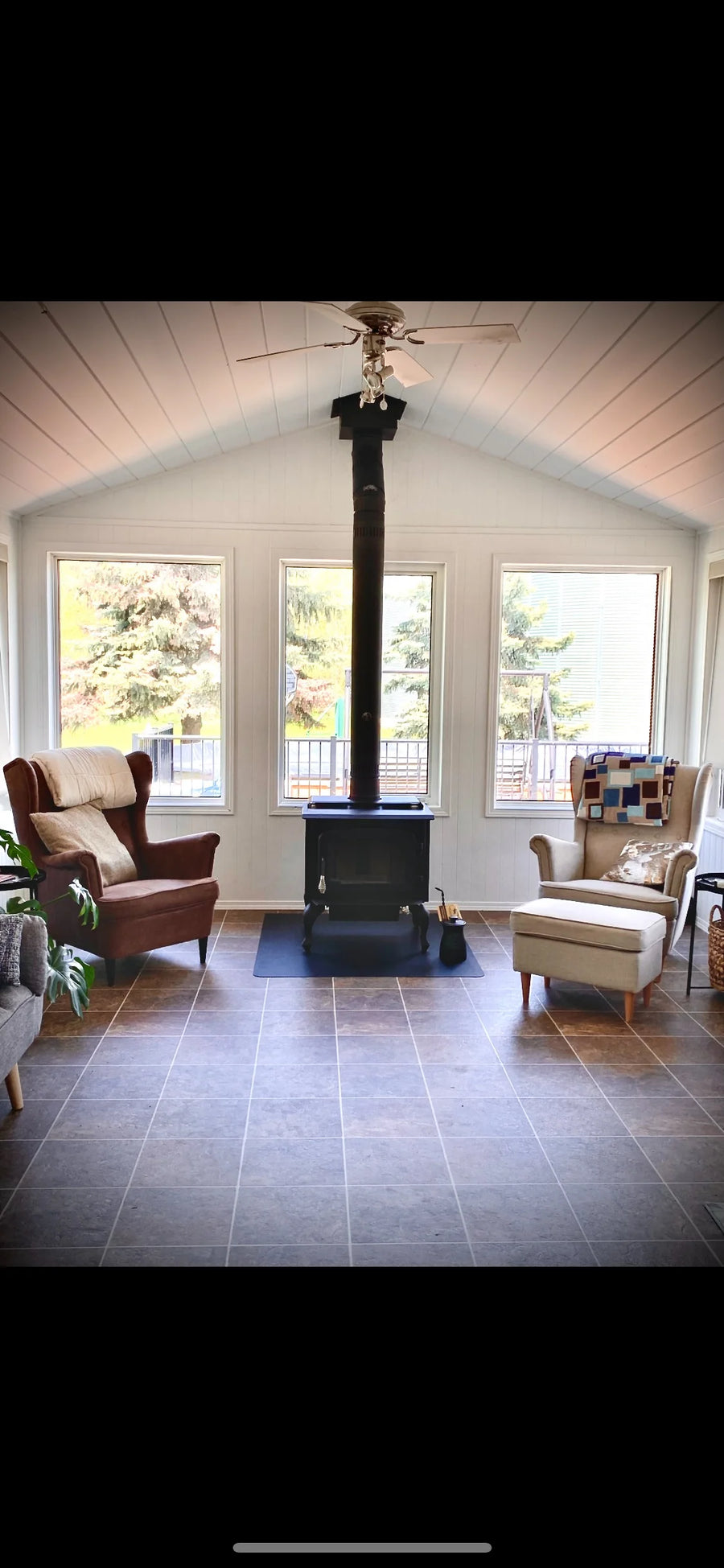 Freestanding wood stove in a bright sunroom, installed by Backwoods